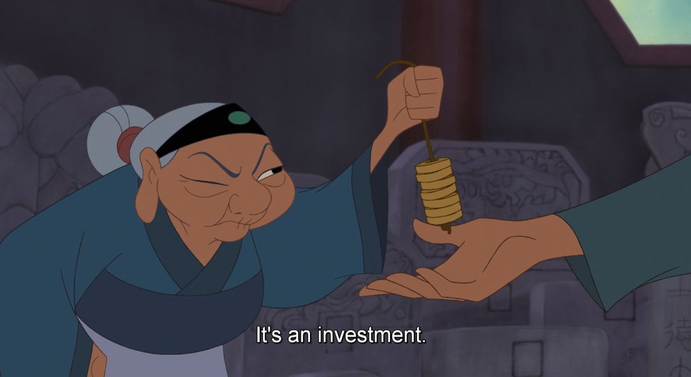In this image, the grandmother from Mulan has a frown on her face and one eye closed because she lost a bet against the father. The father (her son-in-law) has his hand placed out in front of her as a way to collect the money that he won. She is wearing different shades of blue on her outfit and has a headband on with her hair tied back in a tight bun. They appear to be standing in the family's house. 